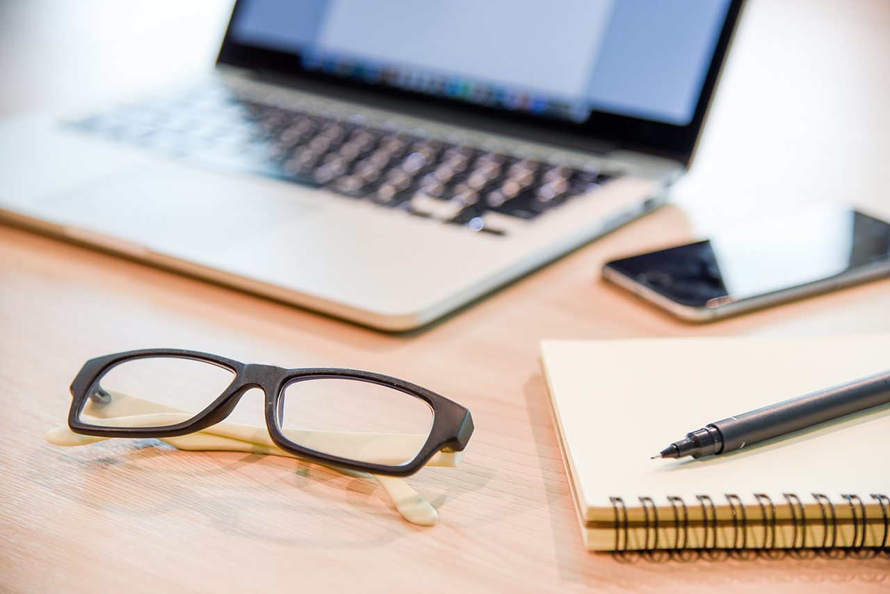 Glasses,-binder-notebook,-pen-and-laptop-on-wooden-office-desk